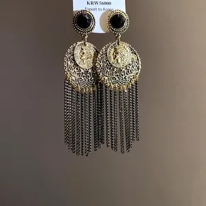 Close-up of vintage gold tassel earrings with hollow filigree and coin medallion details