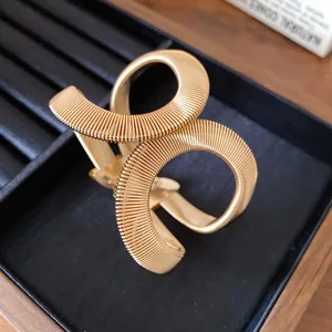 Vista detallada del brazalete cruzado elástico dorado acanalado con diseño de serpiente