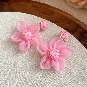 Vista macro detallada de los pendientes de flores de rafia rosa y gasa hechos a mano