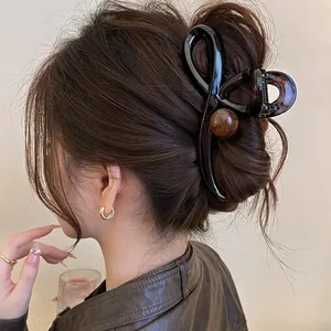 Detailed view of a vintage brown bow hair claw clip styled in a classic bun for thick hair