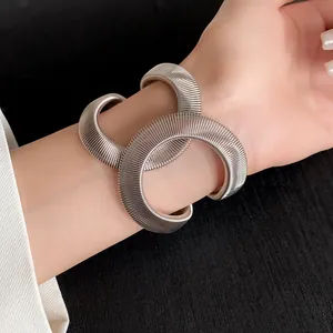 Primer plano de una pulsera de serpiente elástica acanalada plateada en la muñeca de modelo