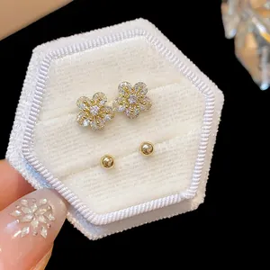 Macro shot of elegant zircon flower and gold ball stud earrings in a velvet box