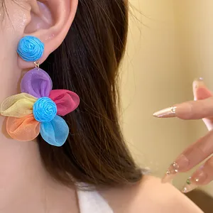 Primer plano de vibrantes pendientes de flores de gasa multicolor en una modelo