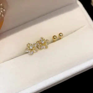 Detail view of sparkling zircon flower earrings and gold ball studs in a jewelry box