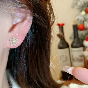 Close-up macro detail of a delicate sparkling gold flower stud earring worn on ear