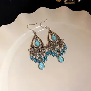 Orecchini vintage bohémien a goccia con strass blu e nappine in stile etnico chic.