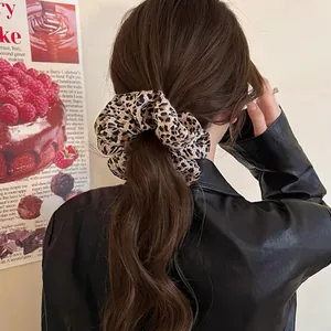 Close-up view of a stylish leopard print fabric scrunchie styling thick long brown hair