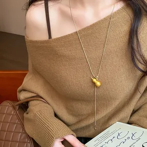 Close-up of brushed gourd pendant sweater chain necklace worn with a brown knit top.