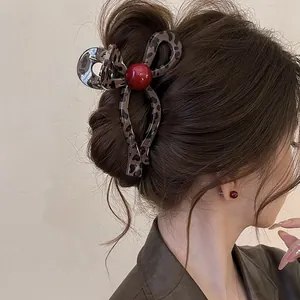 Detailed macro shot of vintage leopard print hair claw clip with red bead on an elegant updo