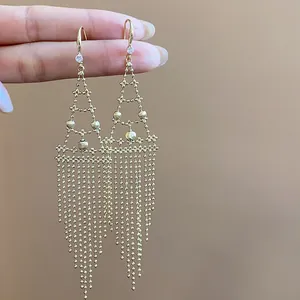 Vista macro detallada de elegantes pendientes de borla dorados con detalles de circonitas