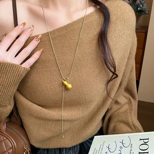 Detailed macro view of brushed gold gourd pendant on a minimalist adjustable chain necklace