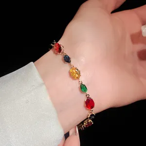 Gros plan d'un bracelet élégant en zircon ovale coloré au poignet avec monture dorée