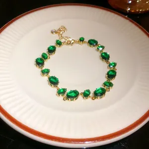 Vue rapprochée détaillée d'un élégant bracelet doré orné de zircons ovales vert émeraude.