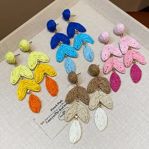 Detailed close-up of bohemian multi-colored raffia woven heart shaped drop earrings