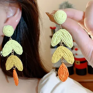 Close-up of colorful raffia woven tiered earrings with silver posts for women.