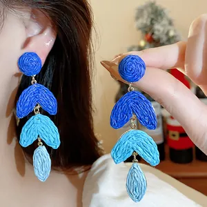 Macro detail of blue gradient raffia straw drop earrings featuring delicate weave texture