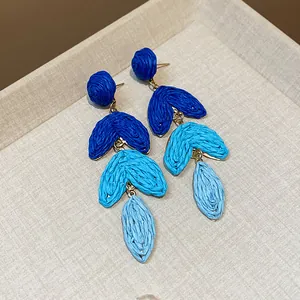 Close-up of blue gradient raffia grass drop earrings with intricate woven texture.