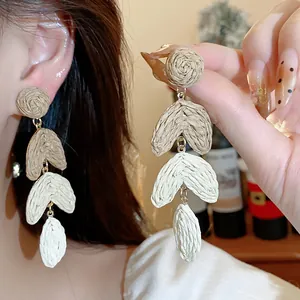 Detailed view of handmade raffia heart drop earrings with a natural bohemian texture.