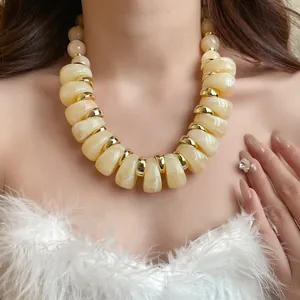 Primer plano de un elegante collar de cuentas acrílicas marmoleadas con detalles dorados.