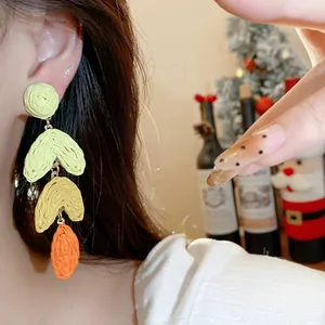 Close-up detail of bohemian layered raffia heart earrings in vibrant dopamine colors