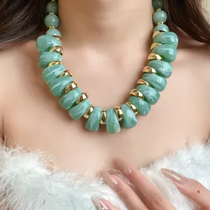 Primer plano de un collar de acrílico verde veteado con detalles dorados
