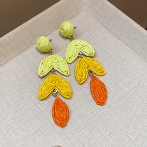 Close-up of handmade raffia heart drop earrings with vibrant dopamine color gradients