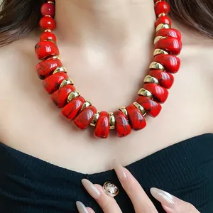 Primer plano de collar acrílico rojo jaspeado con cuentas doradas