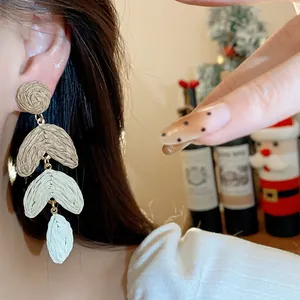 Detailed close-up showing handmade Raffia straw dangling heart earrings worn on an ear
