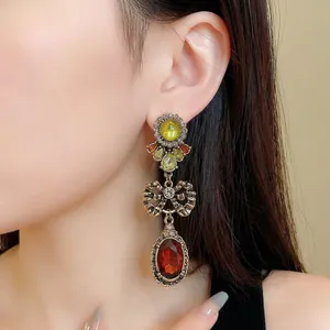 Vintage style bow drop earrings with red oval gemstones worn by an elegant model.