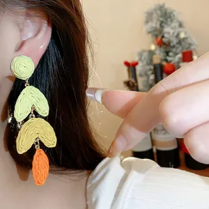 Detailed view of handmade colorful woven raffia dangle earrings with heart-shaped layers