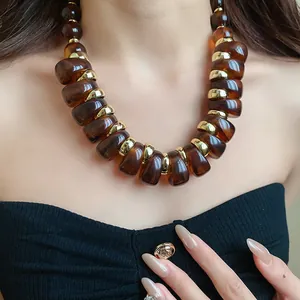 Primer plano de collar de cuentas de acrílico ámbar con anillos dorados en una modelo