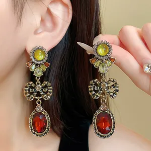 Vintage style drop earrings featuring a detailed bow knot and faceted red oval gemstone