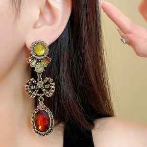 Close-up of vintage-style bow-knot drop earrings with red and yellow rhinestones