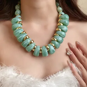 Detalle de collar de cuentas de acrílico verde menta con espaciadores dorados en modelo.