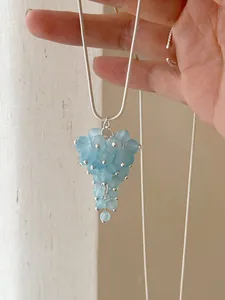 Close-up of light blue glass bead grape-shaped pendant on a silver snake chain