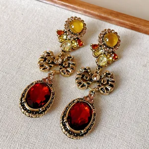 Close-up detail of vintage bowknot drop earrings with large red oval crystals and gold finish