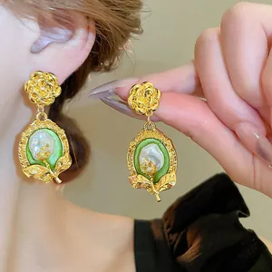 Dettaglio degli orecchini vintage francesi con fiore dorato e goccia di perla.