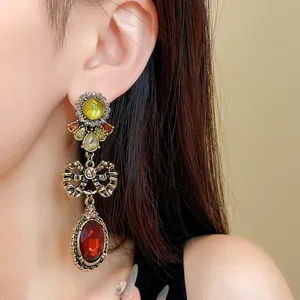 Vintage butterfly bow drop earrings with colorful gemstones worn on an ear profile