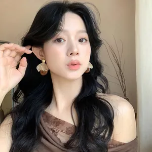 Detailed view of elegant fabric flower and resin drop earrings worn by a model