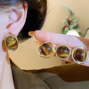 Close-up of vintage gold-plated earrings with brown tiger-eye effect resin stones