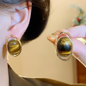 Detail view of Maillard style gold-plated resin earrings with tiger-eye texture.
