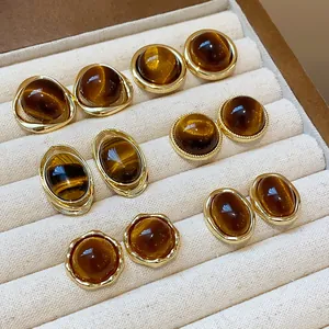 Detailed shot of multiple pairs of gold-plated resin stud earrings in warm brown tones