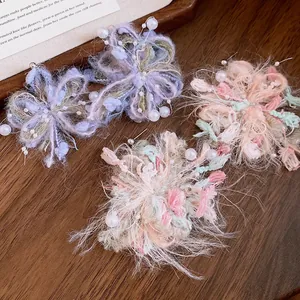 Vista detallada de pendientes de flores de lana hechos a mano con perlas y agujas.