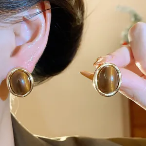 Detail view of elegant gold-plated oval resin stud earrings with cat's eye effect.