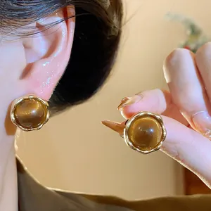 Detail of Maillard style resin stud earrings with gold plated wavy frame on ear.
