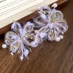 Primer plano de pendientes de flores de lana púrpura con perlas blancas