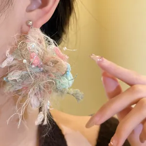 Vista detallada de pendientes de flores de lana hechos a mano con perlas y plata