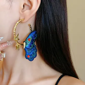 Detailed shot of an elegant gold hoop earring with a vibrant blue embroidered butterfly.