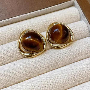Detailed view of gold-plated resin stud earrings with brown Maillard style stones.