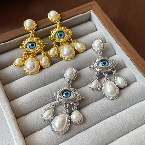 Macro detail of vintage evil eye earrings with textured metal and white faux pearls